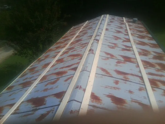 Rusted metal roof panels with new wood purlins before replacement — Storm Damage Roof Repair in Sanders by Roofing Brothers