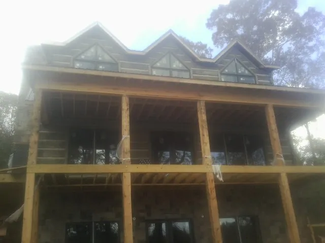 Dormers and porch framing on a large log home under construction — Roof Coating work by our crew in Sanders