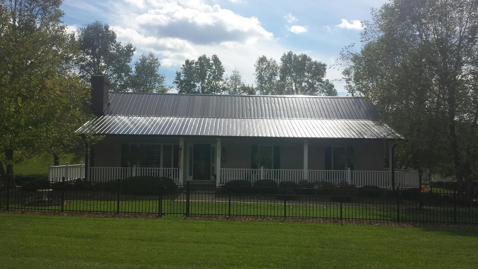 Gray metal roof on a brick ranch with a full width front porch — Gutter Guard Installation work by our crew in Sanders