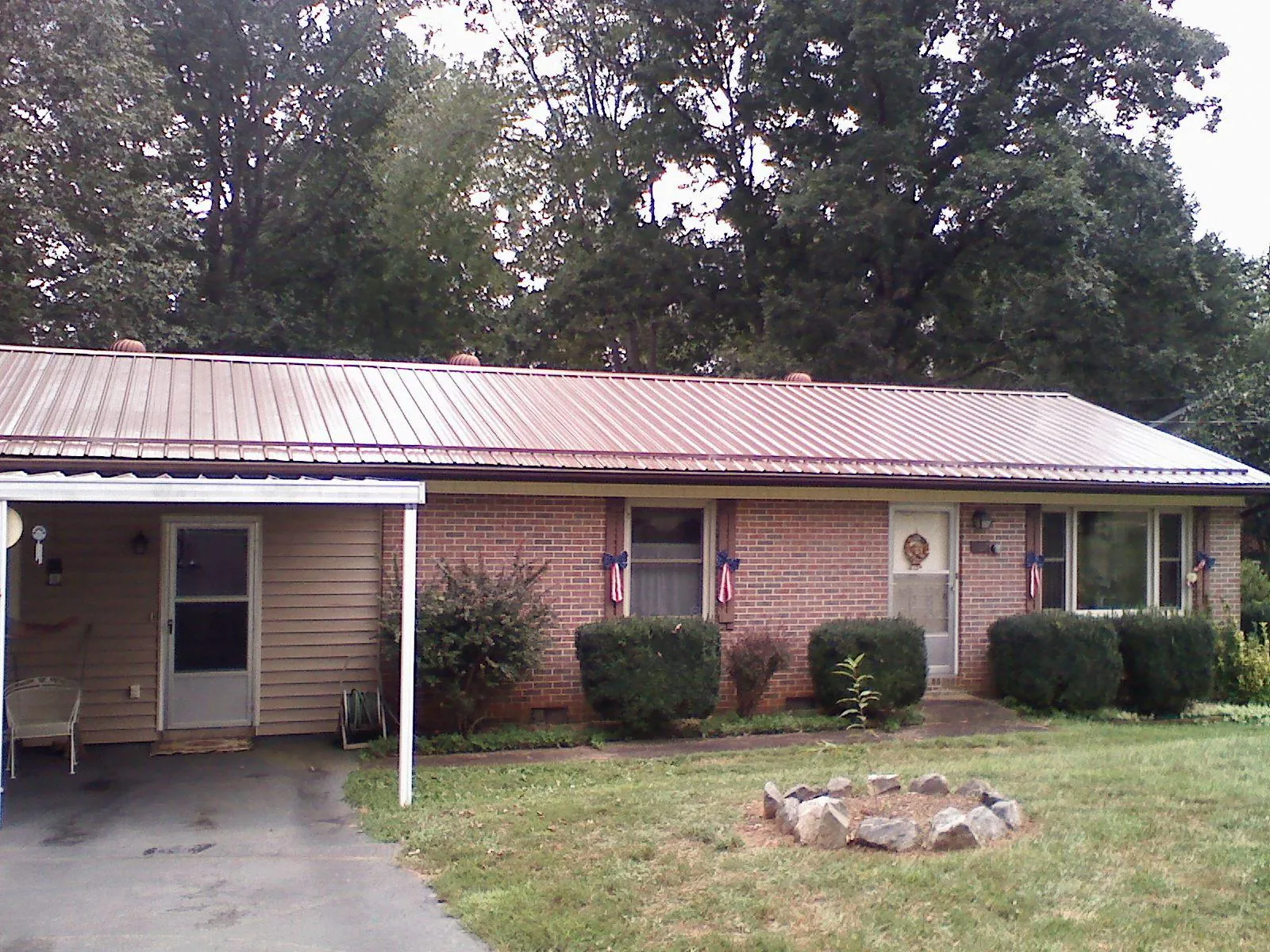 Bronze metal roof and carport on a brick ranch home — Roof Repair work by our crew in Sanders