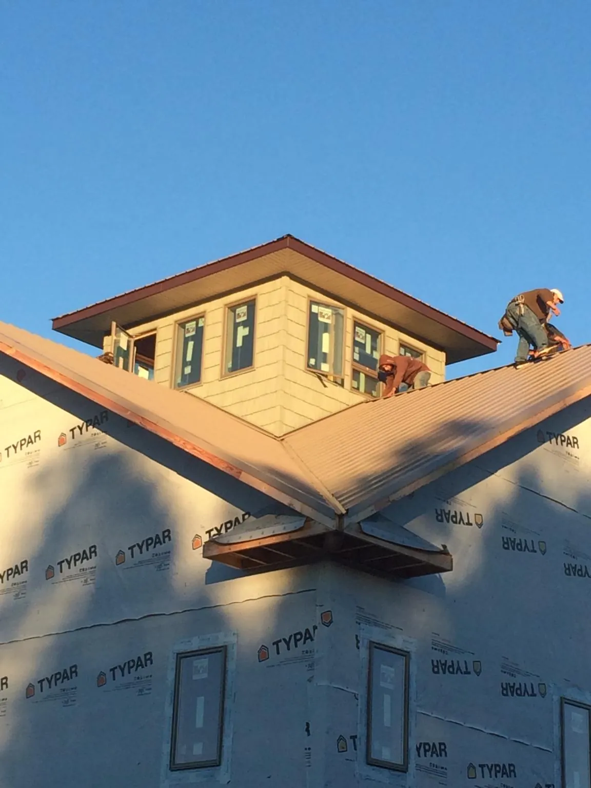 Roofers working around a rooftop cupola on a new metal roof at sunset — Roof Waterproofing in Sanders by Roofing Brothers